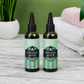Two 100ml bottles of Naiga Naturals Herbal Hair Growth Oil with green labels and black applicator nozzles.
