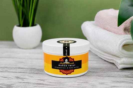 Jar of Mango Twist whipped hair and body butter on a wooden surface with a green background