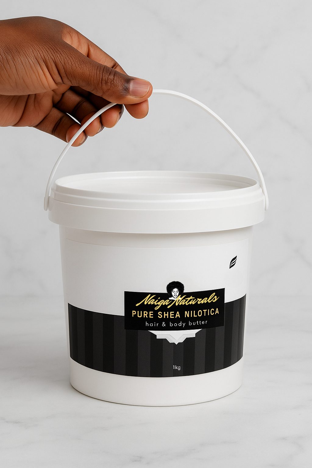White bucket of Shea Nilotica with a black label held by a hand on a light grey background