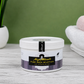 Jar of Naiga Naturals Pure Shea Nilotica body butter on a wooden surface with a green background.