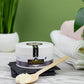 Naiga Naturals Pure Shea Nilotica butter jar and a spoonful of shea butter beside folded towels and a potted plant.