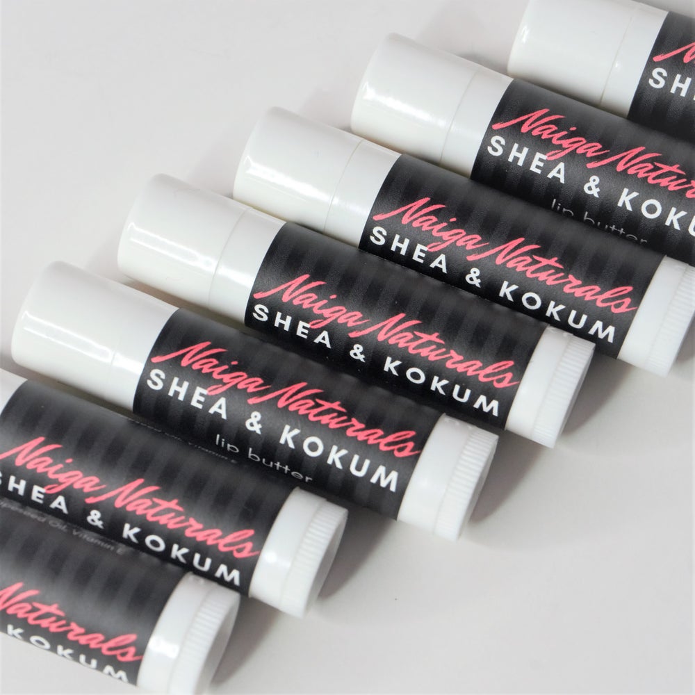 Close-up of Naiga Naturals Shea and Kokum Lip Butter tubes arranged diagonally, showing their black and pink labels.
